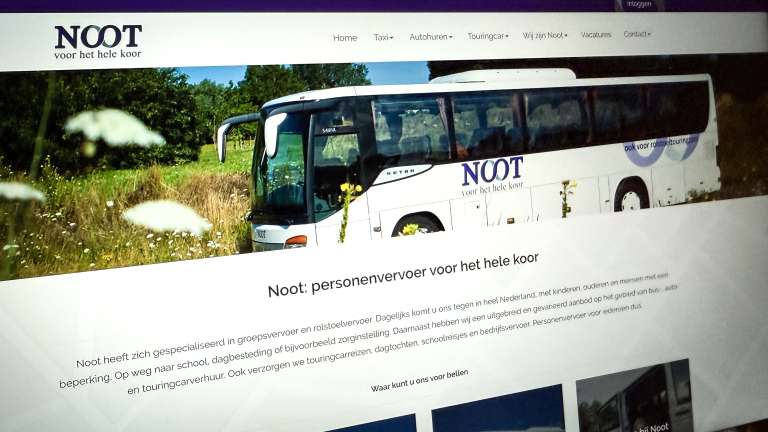 Scherm van een website met de titel "Noot: personenvervoer voor het hele koor", met afbeelding van een witte touringcarbus van het bedrijf Noot, omgeven door gras en bloemen.