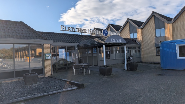 Vooraanzicht van Fletcher Hotel met een glazen entree en luifel met het woord 'Entree'.