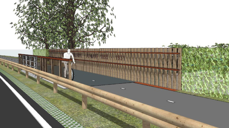 Fietser op een fietspad naast een houten hek met de tekst "1939-1945" en een grote boom op de achtergrond.