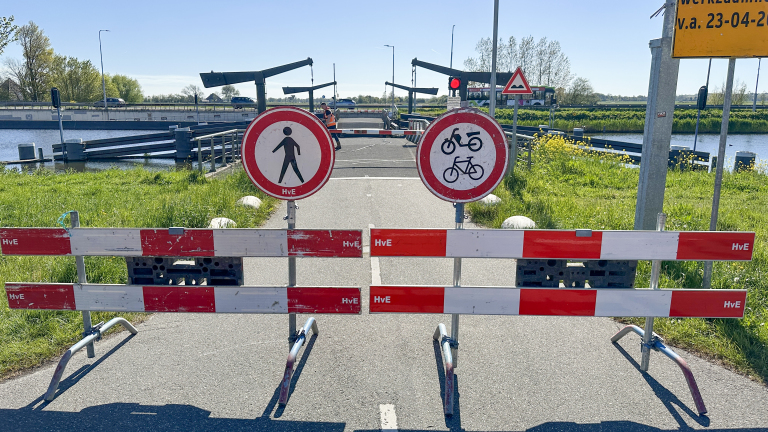 Twee verkeersborden en een wegafsluiting blokkeren een pad; de borden verbieden voetgangers en fietsers/motorfietsen.