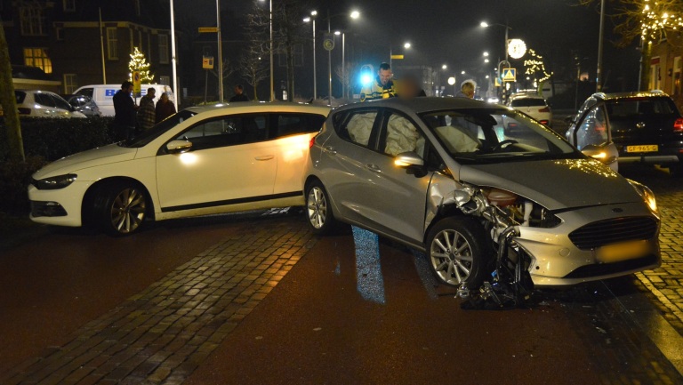 Twee auto's betrokken bij een botsing op een straat 's nachts, met zichtbaar schade aan de voorzijde van de zilveren auto.