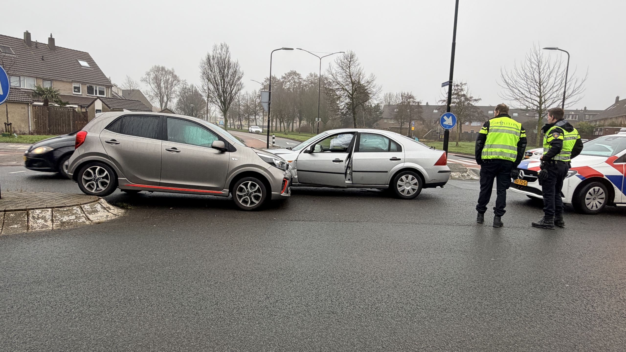 Twee auto's met schade na een botsing, met politieagenten die de situatie bekijken.