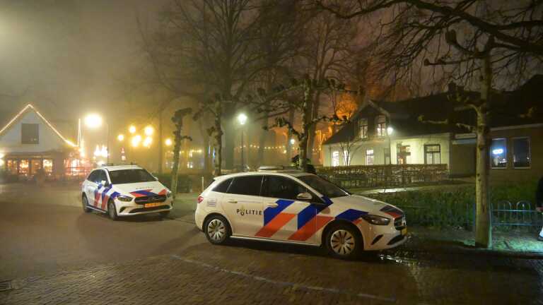 Een ambulance staat geparkeerd op een mistige straat met een paramedicus die naast het voertuig staat.