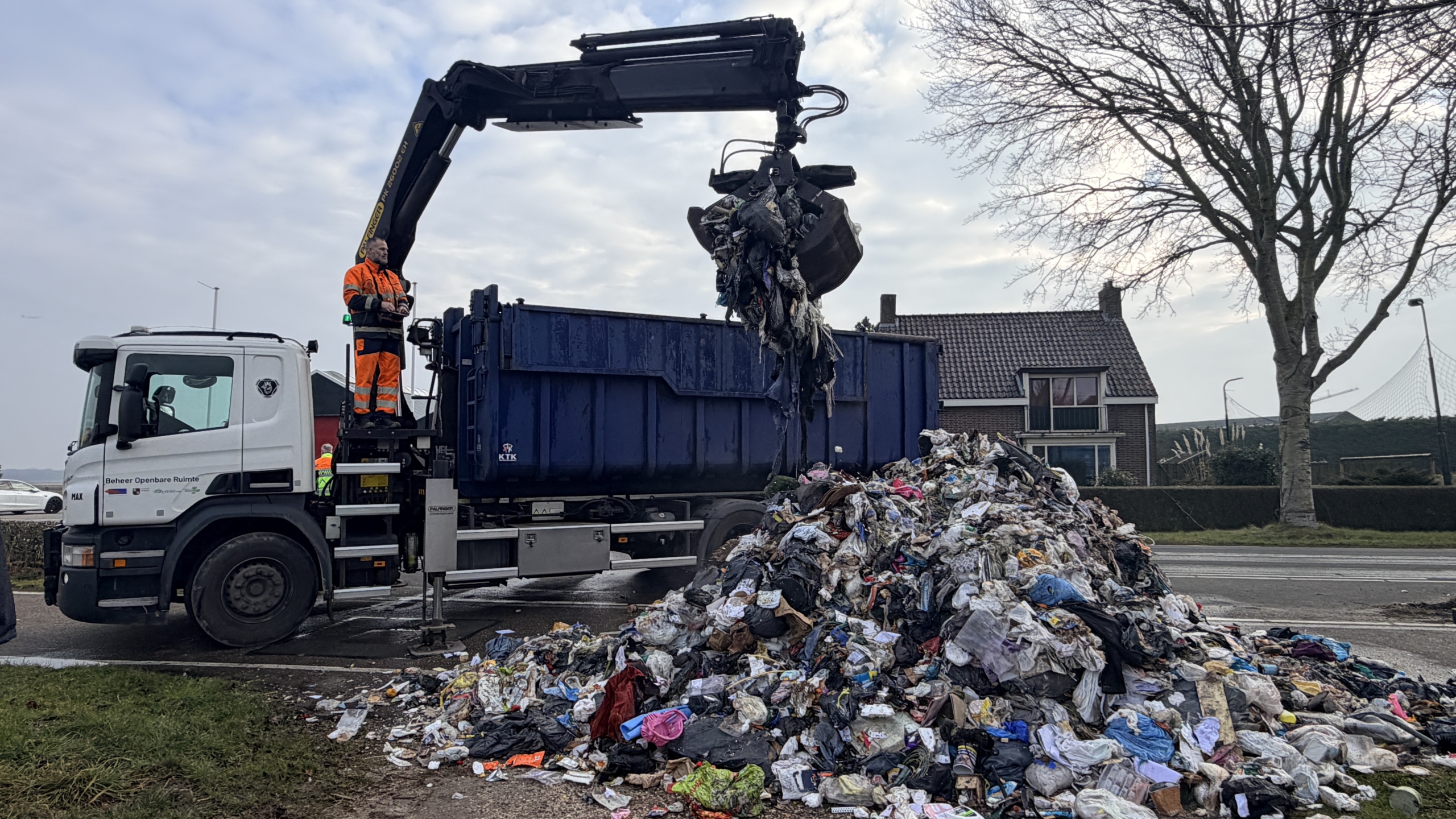 Vuilnis ligt verspreid over de weg na een ongeluk met een vuilniswagen; hulpverleners en verkeersdienst ter plaatse.