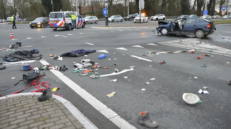 Auto-ongeluk op een kruispunt, met een beschadigde auto, verspreide brokstukken en politie ter plekke.