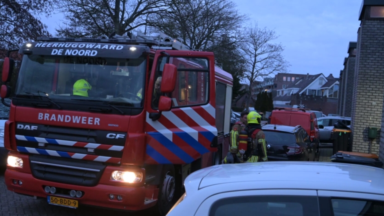 Brandweerlieden in uitrusting met zuurstofflessen betreden een gebouw door een open deur.