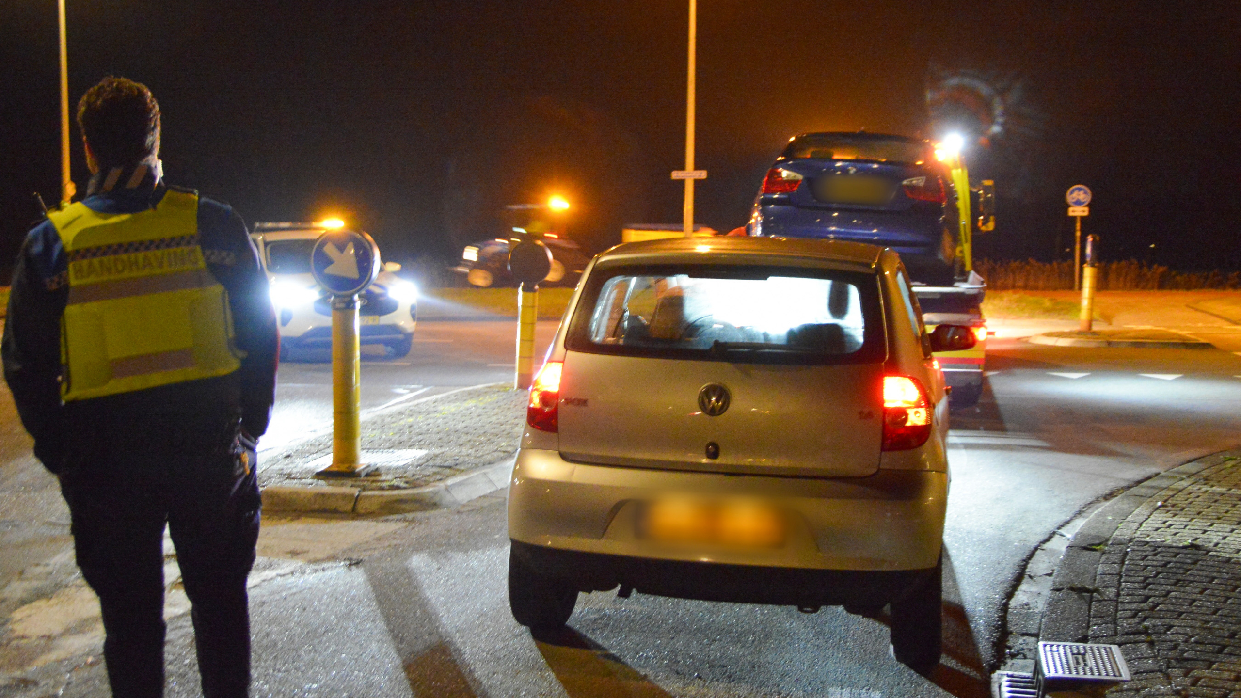 Auto-ongeluk bij nacht op kruispunt, met schade aan twee voertuigen; man in veiligheidskleding onderzoekt de situatie.