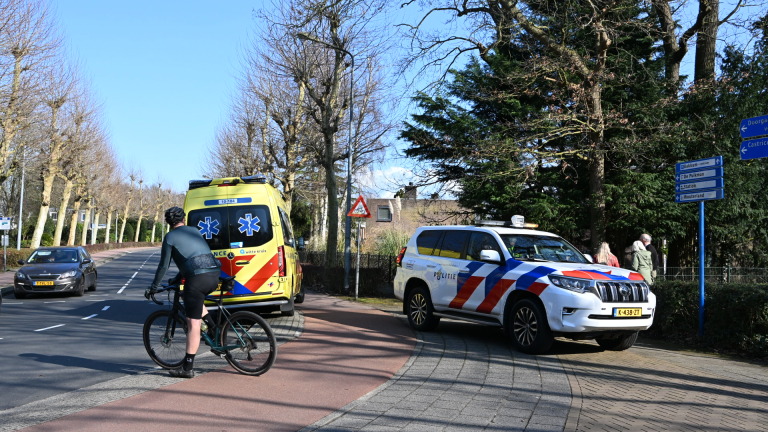 Een zilveren auto is tegen een boom gereden met de airbags uitgeklapt; enkele mensen staan er omheen te kijken.