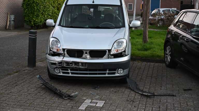 Politieagenten naast een politieauto in een woonwijk, deels verlicht door koplampen van andere auto's.