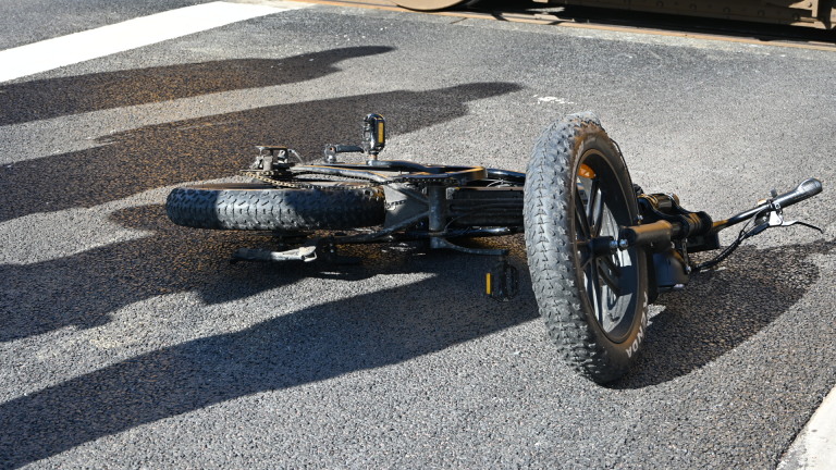 Een gele en blauwe passagierstrein staat bij een spoorwegovergang met politie- en spoormedewerkers op de voorgrond.