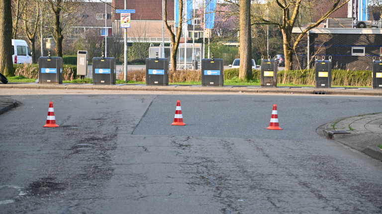 Twee gele ambulances met rode en blauwe strepen staan geparkeerd in een woonstraat, omringd door bomen en huizen.