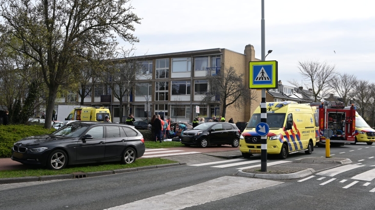 Hulpverleningsvoertuigen en mensen verzamelen zich bij een ongevalslocatie voor een gebouw.