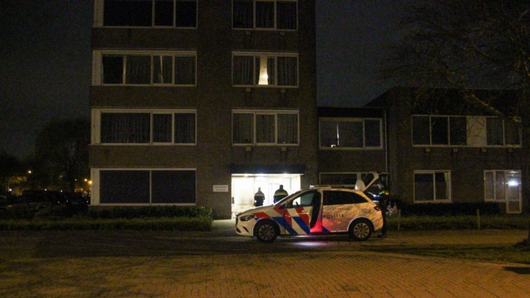 Bankje en gebroken glazen deur in een beschadigde hal met roet op het raam.