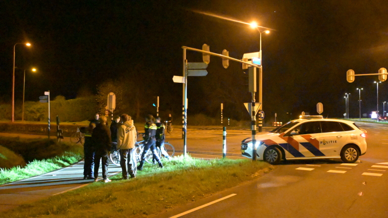 Een ambulance en een politiewagen bij een kruispunt met verkeerslichten 's nachts.