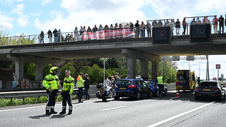 Politie en hulpdiensten bij een ongeval onder een brug in Heiloo, met toeschouwers bovenop de brug en een ambulance ter plaatse.