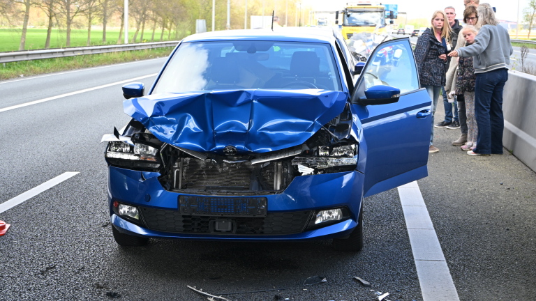 Politie en hulpdiensten bij een ongeval onder een brug in Heiloo, met toeschouwers bovenop de brug en een ambulance ter plaatse.