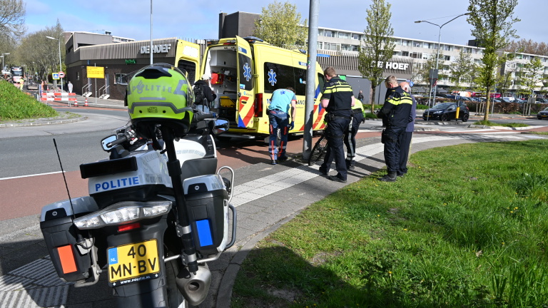 Politieagenten en ambulancepersoneel bij een ongeval; politie motorfiets op de voorgrond, met een geopende ambulance op de achtergrond.