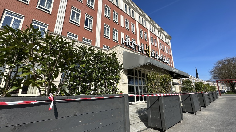 Gevel van Hotel Alkmaar met bakstenen muren, grote ramen en een rij heggen ervoor.