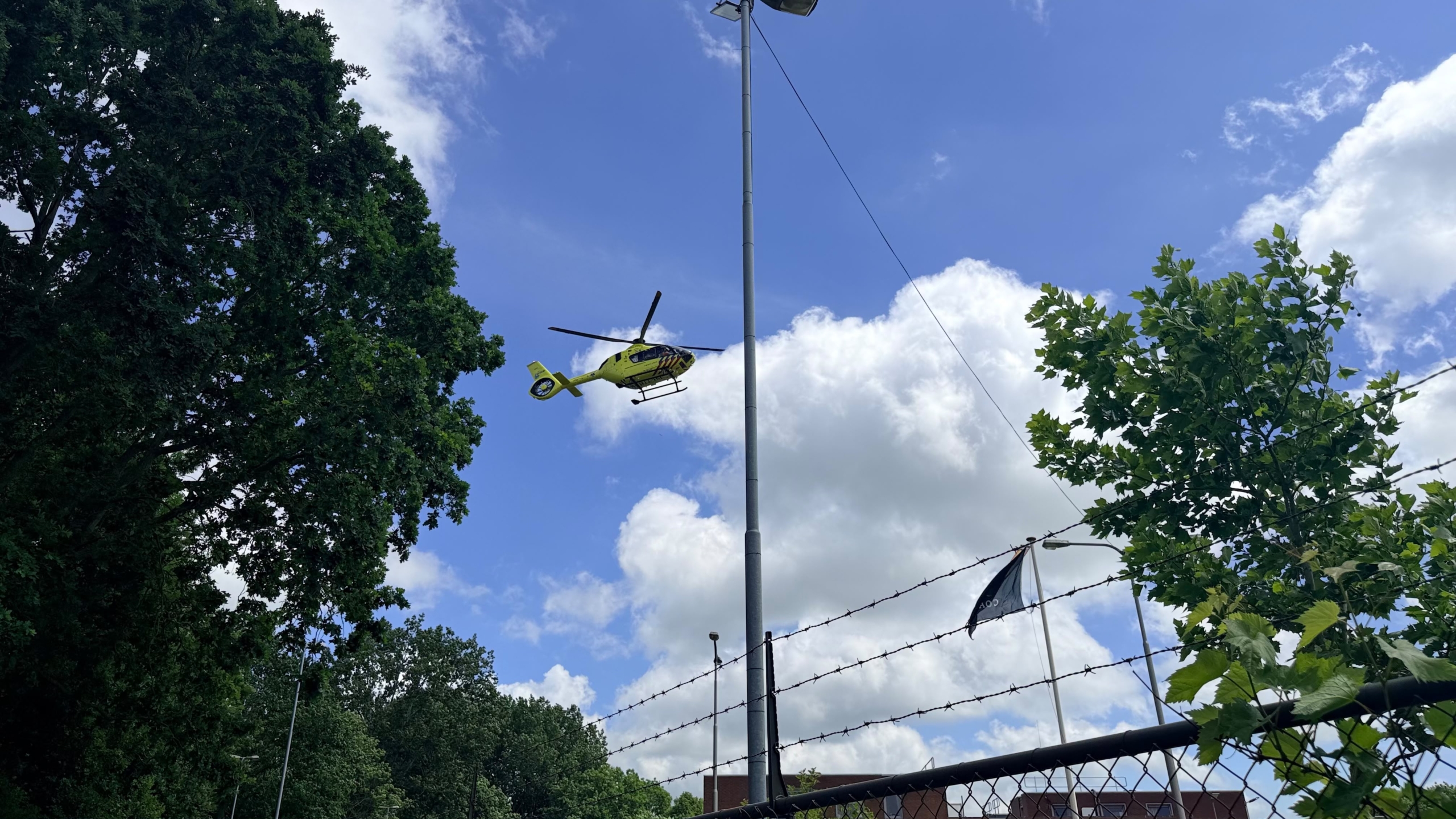 Politie- en ambulances staan geparkeerd bij een gebouw, met een persoon in een BHV-vest op de voorgrond.
