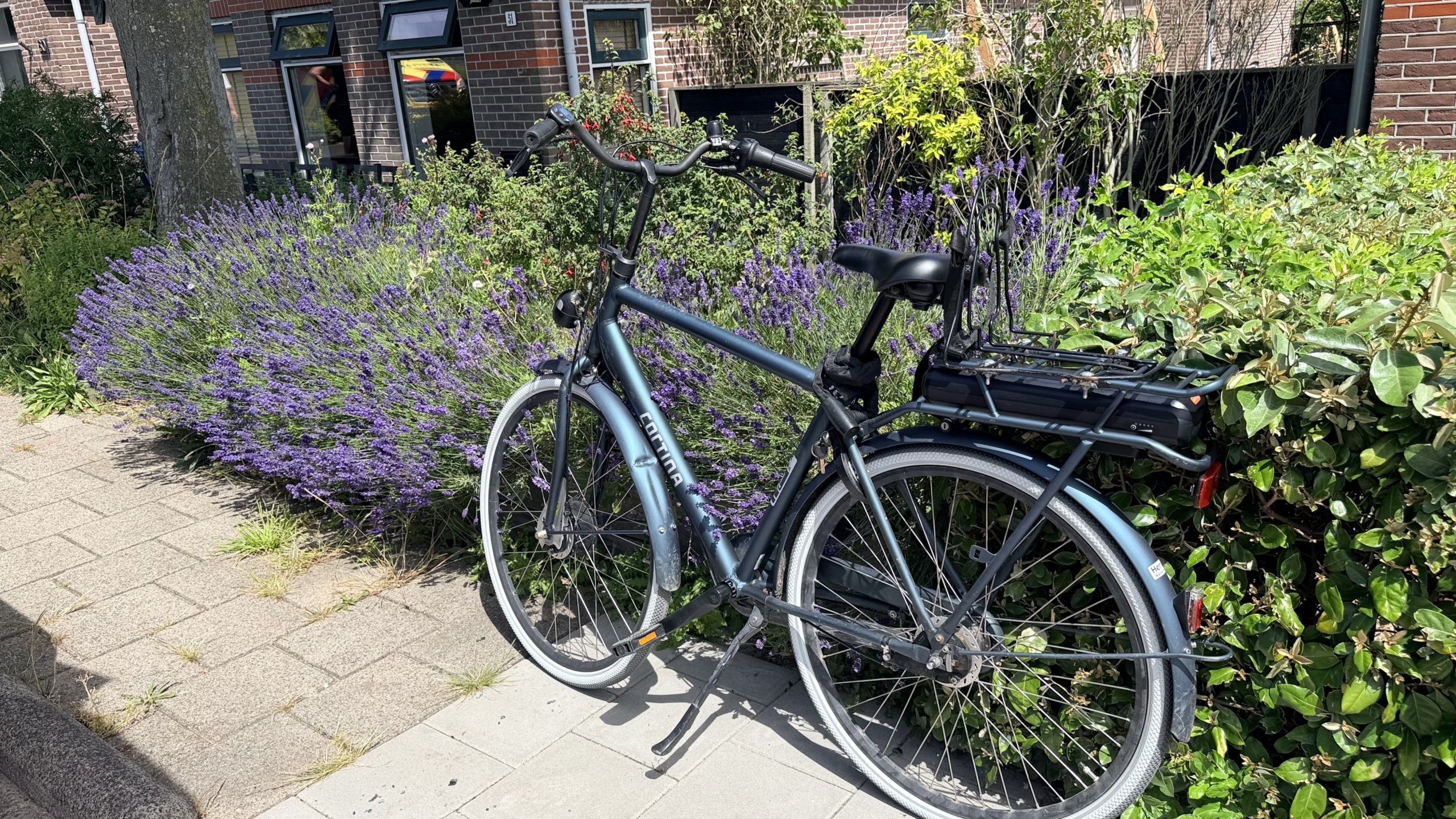 Politieagenten onderzoeken glasscherven op een fietspad naast een geopende bestelwagen, in een landelijke omgeving.