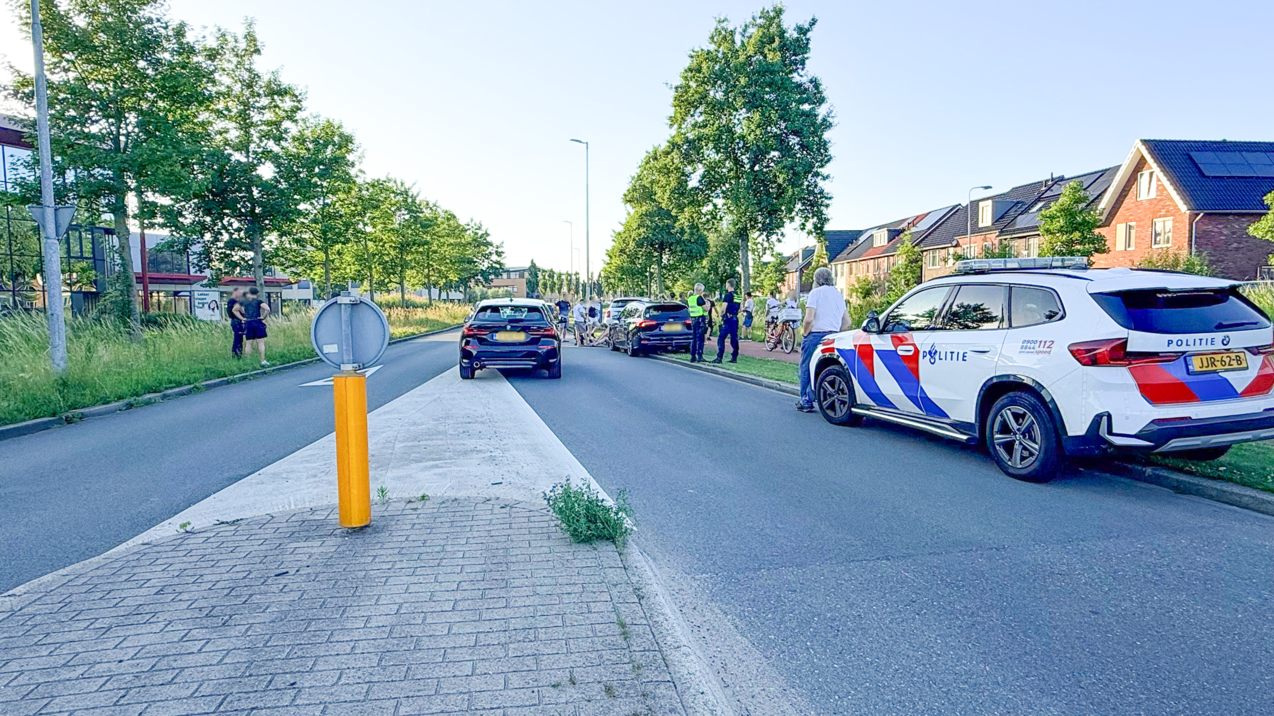 Politie- en handhavingsvoertuigen staan langs de weg, waar agenten met een groep mensen bezig zijn.