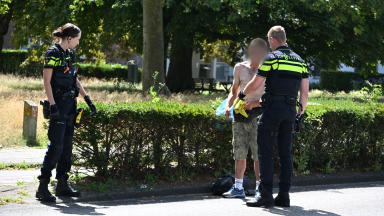 Twee Nederlandse politieauto’s met zwaailichten langs de weg, agenten staan bij open achterdeuren tijdens een controle