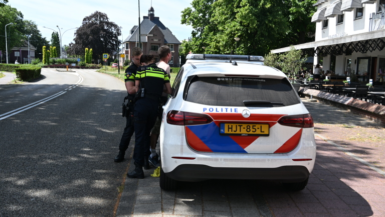 Twee Nederlandse politieauto’s met zwaailichten langs de weg, agenten staan bij open achterdeuren tijdens een controle