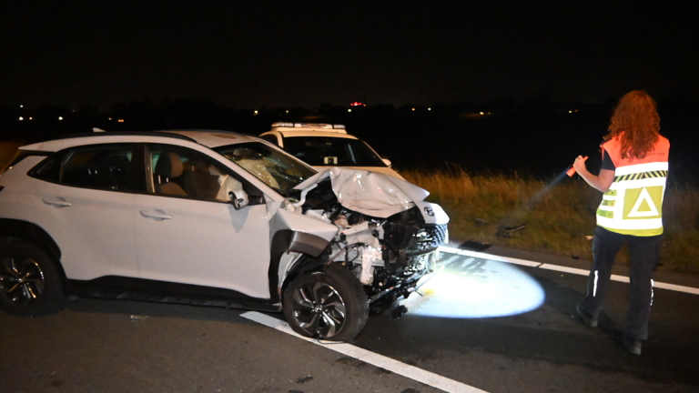 Nachtelijk verkeersongeval met zwaar beschadigde auto, politieagenten, ambulance en politiewagen met zwaailicht