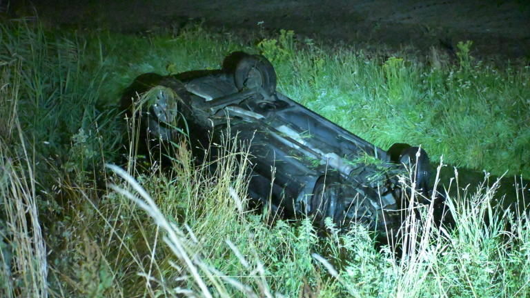 Nachtelijk verkeersongeval met zwaar beschadigde auto, politieagenten, ambulance en politiewagen met zwaailicht