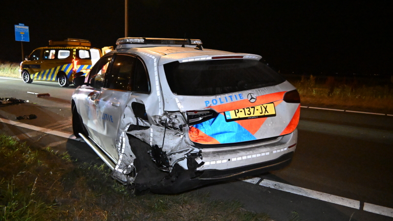 Nachtelijk verkeersongeval met zwaar beschadigde auto, politieagenten, ambulance en politiewagen met zwaailicht