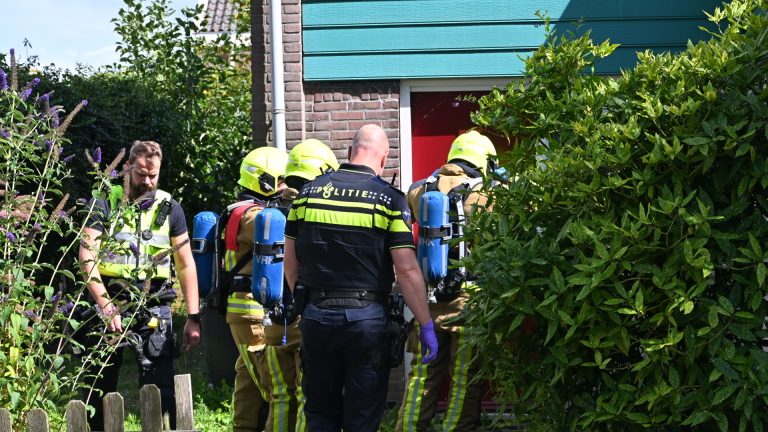 Brandweerwagen en twee politieauto’s staan langs een woonstraat met hulpverleners bij de voertuigen