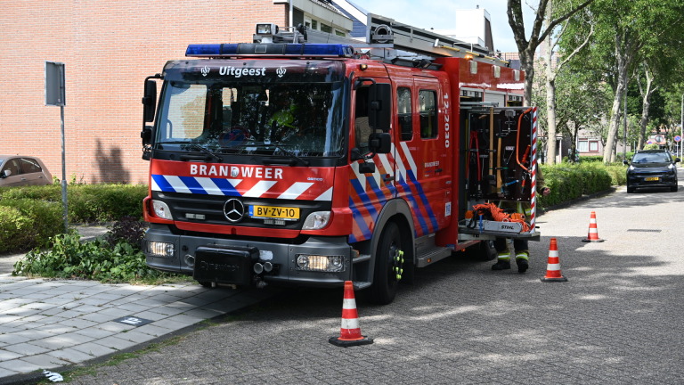 Brandweerwagen en twee politieauto’s staan langs een woonstraat met hulpverleners bij de voertuigen