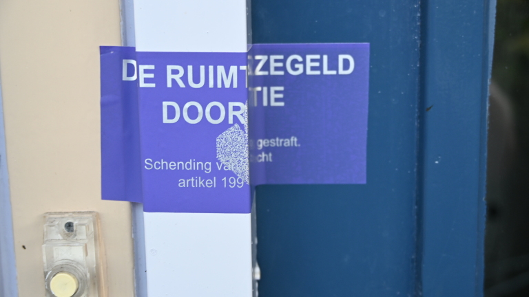 Politieauto en ambulance geparkeerd in een woonstraat met huizen en bomen, met meerdere auto’s langs de weg