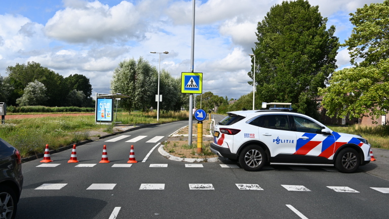 Politiemotor blokkeert de weg terwijl ambulance en hulpverleners verderop bij een incident in een woonwijk staan