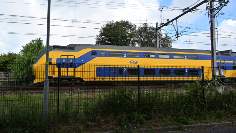 Twee brandweerlieden lopen over een tramhalte richting poortjes; rechts staat een politiemotor geparkeerd