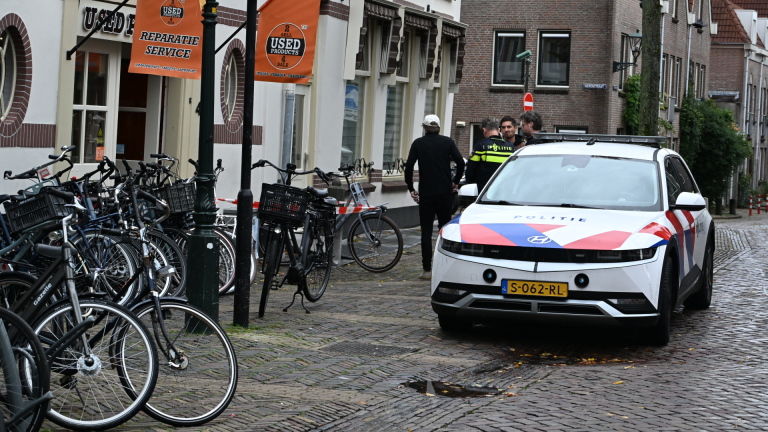 Politieauto en agent bij met lint afgezet winkelpand “Used Products”, met fietsen voor de ingang