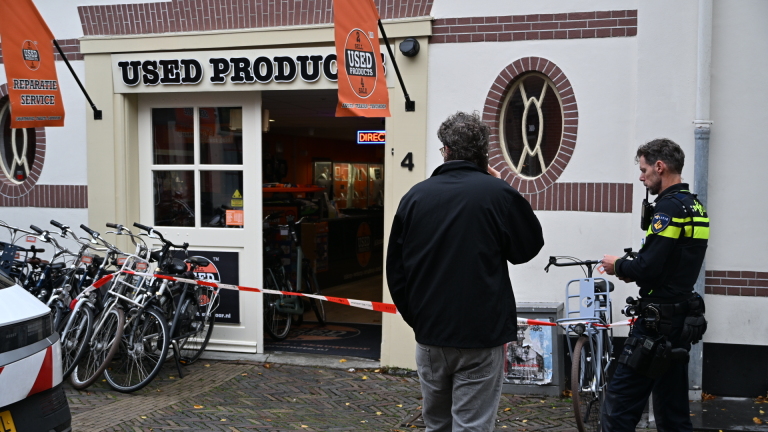 Politieauto en agent bij met lint afgezet winkelpand “Used Products”, met fietsen voor de ingang